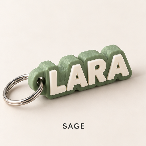 Sage green name keychain with raised white letters spelling LARA on a silver key ring