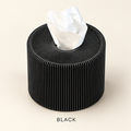 Round black ribbed tissue box cover with a tissue coming out of the top opening