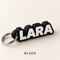 Black name keychain with raised white letters spelling LARA on a silver key ring