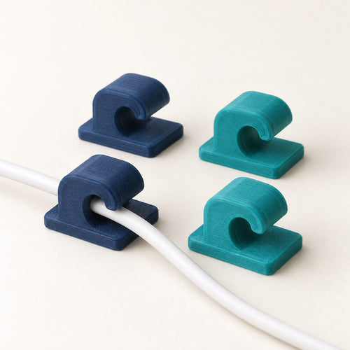 Four desk cable clips, two navy and two teal, two of them holding a white charging cable