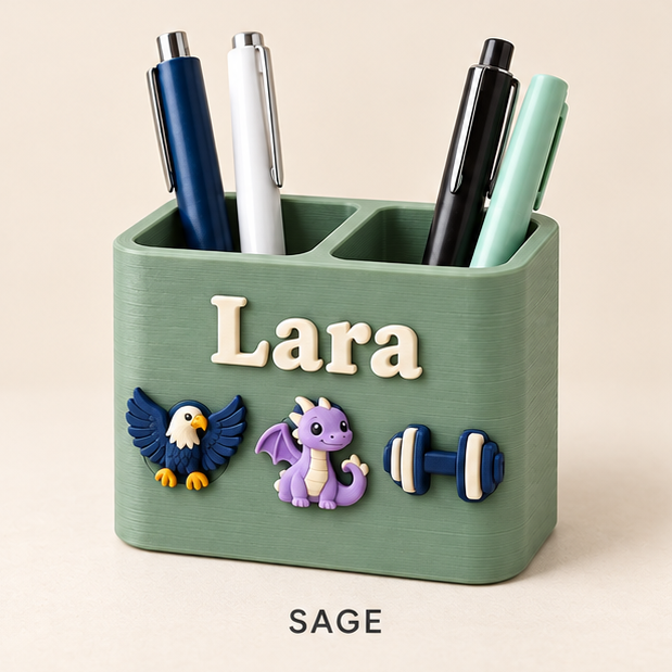 Sage green two-slot pen holder with the name Lara and eagle, dragon and dumbbell charms on the front