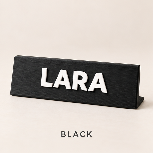 Black desk nameplate with raised white letters spelling LARA